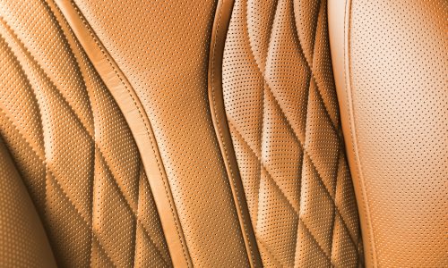 Perforated leather texture background for design, orange summer. Texture, color, artificial leather with stitching