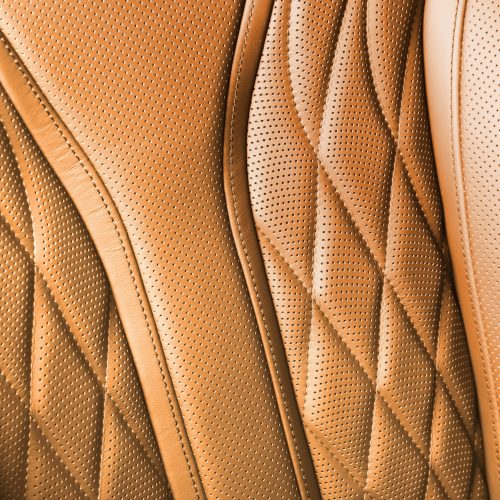Perforated leather texture background for design, orange summer. Texture, color, artificial leather with stitching